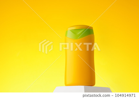 Cosmetic bottle with sunscreen lotion on yellow background 104914971