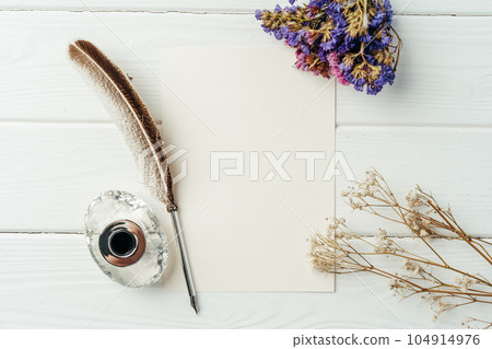 Blank letter, dry flowers and antique feather pen on wooden background Blank letter, dry flowers and antique feather pen on wooden background 104914976