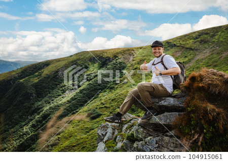 Man on top of a mountain sitting on a rock 104915061