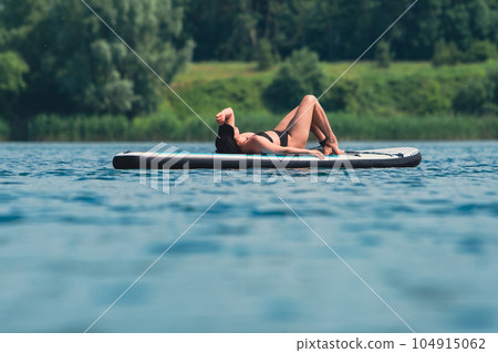 woman in swimming suit sunbathing on supboard woman in swimming suit sunbathing on supboard 104915062