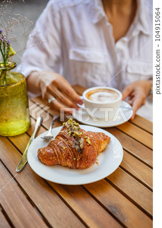 French breakfast made of a croissant and a cup of coffee on the summer terrace in the cafe French breakfast made of a croissant and a cup of coffee on the summer terrace in the cafe 104915064