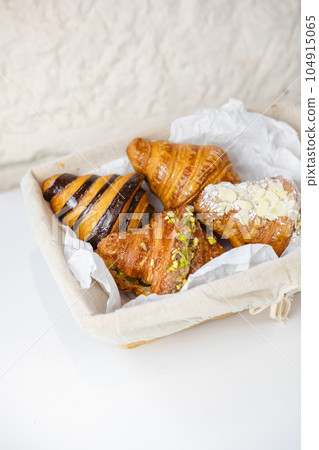 four types of croissants in a basket on a white table 104915065