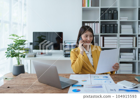 Consultant, advisor, Asian business woman working on the computer and using smartphone mobile talking work financial and marketing business planning company profits, marketing planning budget 104915593