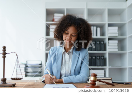 Young African American lawyer studying a case for a client and signing a legal contract to fight her opponent in court. Legal and lawyer concepts 104915626