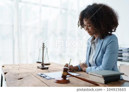 Young African American lawyer studying a case for a client and signing a legal contract to fight her opponent in court. Legal and lawyer concepts 104915683