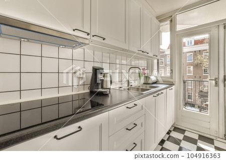 a kitchen with black and white tiles on the counter tops, along with an open door that leads to a patio 104916363