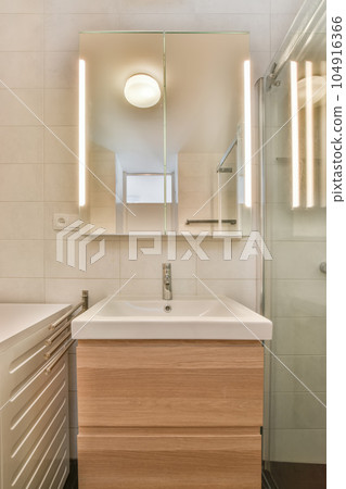 a bathroom with a sink, mirror and light on the wall above it is an image of a glass shower door 104916366