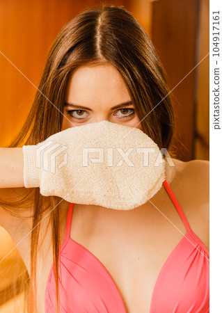 Woman in sauna with exfoliating glove. Skincare. Woman in sauna with exfoliating glove. Skincare. 104917161