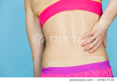 Woman with medical kinesio taping on back Woman with medical kinesio taping on back 104917536