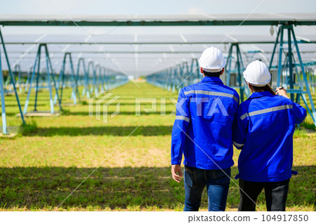 Workers installing solar panels, Engineer team at solar panel farm 104917850