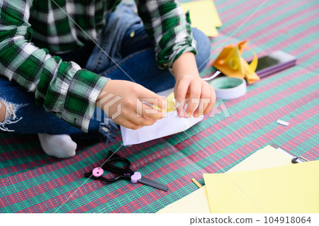 Happy girl making paper toy and playing in garden on weekend 104918064