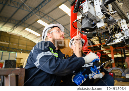 Mechanical engineers repairing engine machine at factory 104918084