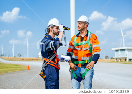 Professional engineers technicians working at wind turbine farm field 104918289