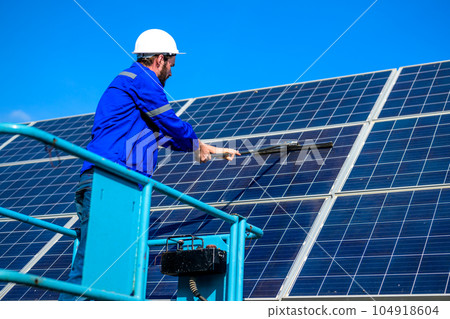 Worker cleaning solar panel at solar cell farm Worker cleaning solar panel at solar cell farm 104918604
