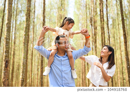 Cute girl riding on father shoulder playing together on holiday Cute girl riding on father shoulder playing together on holiday 104918768