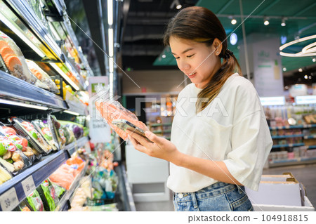 Young adult woman using phone in grocery store 104918815