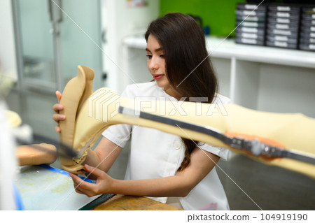 Technician making prototype of prosthetic leg, Artificial metal limb 104919190