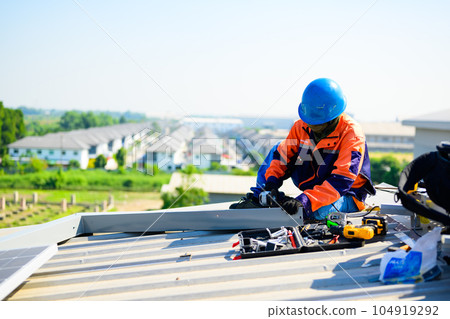 Male technician worker installing solar panels on rooftop of industrial plant Male technician worker installing solar panels on rooftop of industrial plant 104919292