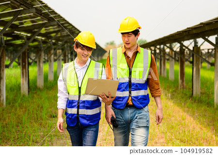 Maintenance engineers checking solar panels on solar cell farm 104919582