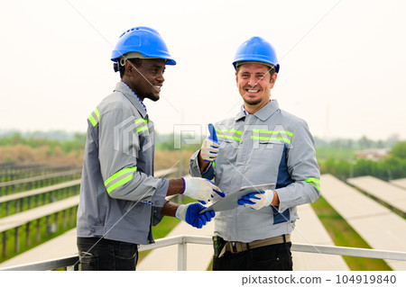 Happy maintenance engineers checking and maintaining solar panels 104919840