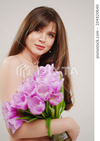 a gentle woman topless with tulips on a white background. 104920640