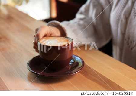 Woman with aromatic coffee at table in cafe, closeup 104920817