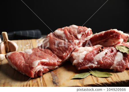 Raw ribs with bay leaves and salt on wooden board, closeup 104920986