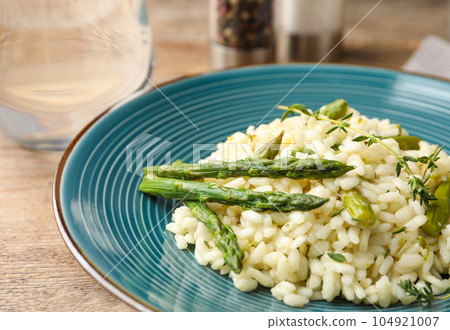 Delicious risotto with asparagus served on wooden table, closeup Delicious risotto with asparagus served on wooden table, closeup 104921007