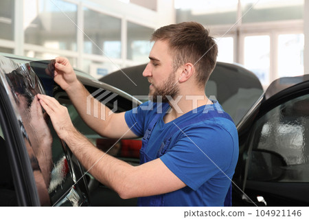 Worker tinting car window with foil in workshop 104921146