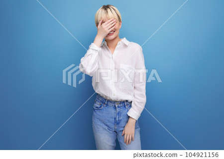 portrait of a confused young pretty blond business woman in a white blouse and jeans on a background 104921156