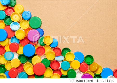 Colorful bottle caps background cardboard box. Used PET recycling plastic bottle cap plastic lids. Garbage PET waste recycling bottle cap sorting waste plastic garbage collection. Recyclable materials Colorful bottle caps background cardboard box. Used PET recycling plastic bottle cap plastic lids. Garbage PET waste recycling bottle cap sorting waste plastic garbage collection. Recyclable materials 104921340