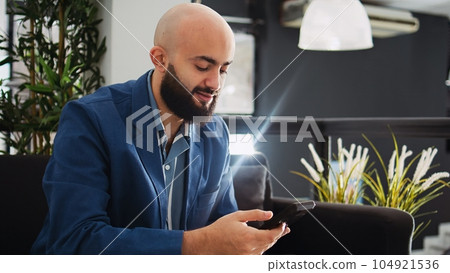 Manager examine sales statistics in startup business coworking space, looking at annual data reports on smartphone. Employee analyzing company information in office, successful entrepreneur. 104921536