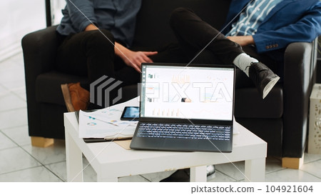 Online agency analytics on laptop in coworking space, running program with sales statistics for unicorn business development. Successful investment plan with marketing data on device. 104921604