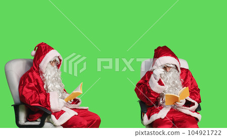 Santa claus reading fiction book in studio, enjoying literature or poetry lecture for knowledge. Saint nick sitting on chair with fairytale story in hand, greenscreen backdrop. Santa claus reading fiction book in studio, enjoying literature or poetry lecture for knowledge. Saint nick sitting on chair with fairytale story in hand, greenscreen backdrop. 104921722