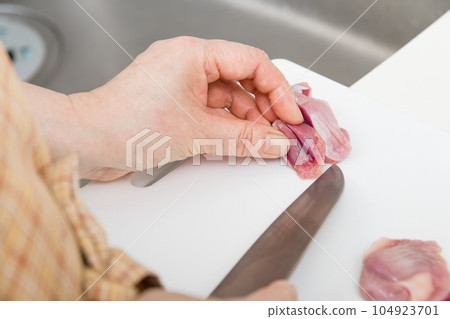[Housewife preparing yakitori gizzards with a knife] 104923701