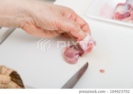 [Housewife preparing yakitori gizzards with a knife] 104923702