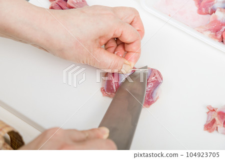 [Housewife preparing yakitori gizzards with a knife] 104923705