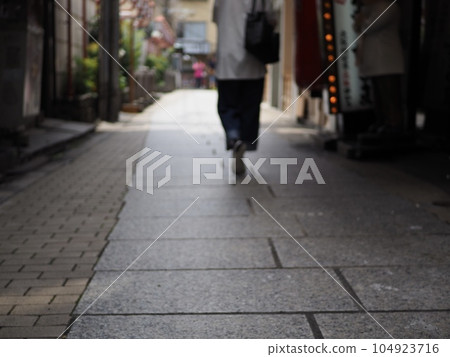 A person walking on a stone pavement on a rainy day A person walking on a stone pavement on a rainy day 104923716