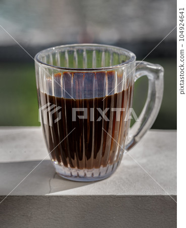 Espresso coffee in glass cup on wooden table with nature view background. Espresso coffee in glass cup on wooden table with nature view background. 104924641