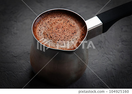 coffee with brown froth brewed in cezve on dark gray background 104925160