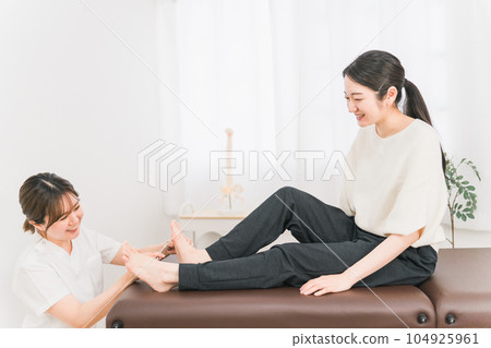 A woman in a white coat and a patient who treats corns and calluses on the soles of the feet A woman in a white coat and a patient who treats corns and calluses on the soles of the feet 104925961