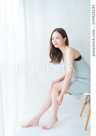 Young woman sitting on a chair and doing leg skin care and massage Young woman sitting on a chair and doing leg skin care and massage 104928195