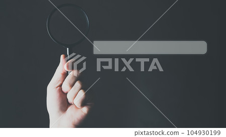 Search Engine Optimization, Search bar on virtual screen with hand holding magnifying glass. 104930199