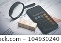 Tax word on wooden block with phone app calculator and magnifying glass. 104930240