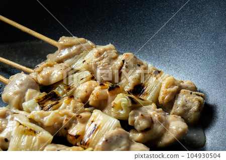 將烤雞肉串(negima 串)在煎鍋中重新加熱(與清酒)的烹飪場景。 將烤雞肉串(negima 串)在煎鍋中重新加熱(與清酒)的烹飪場景。 104930504