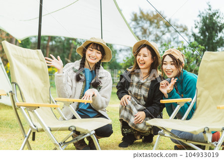 Female camper assembling and tidying up camping chairs Female camper assembling and tidying up camping chairs 104933019