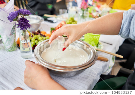 Making cheese from goat milk at home. Female and stir cheese sourdough with a spoon in a saucepan. Technology of cooking cheese. Cheese-making processes. Cooking concept 104933127