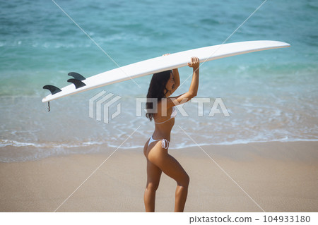 Enjoying the Sun and Surf: Young Woman Embracing Adventure on a Tropical Beach Enjoying the Sun and Surf: Young Woman Embracing Adventure on a Tropical Beach 104933180