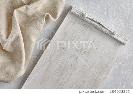 White painted wooden tray and coarse linen kitchen napkin on light stone table. Top view with copy space White painted wooden tray and coarse linen kitchen napkin on light stone table. Top view with copy space 104933205