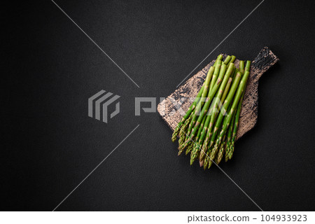 Delicious fresh sprigs of asparagus on a dark textured background 104933923